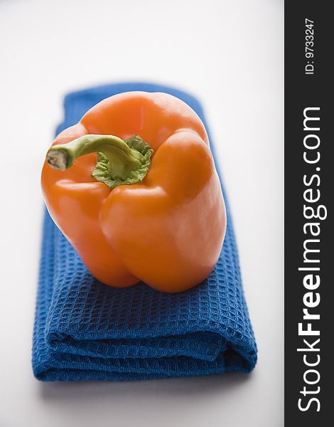 Orange pepper on a 	blue tablemats