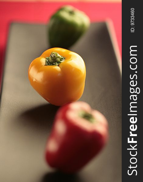 Closeup colored peppers on black plate