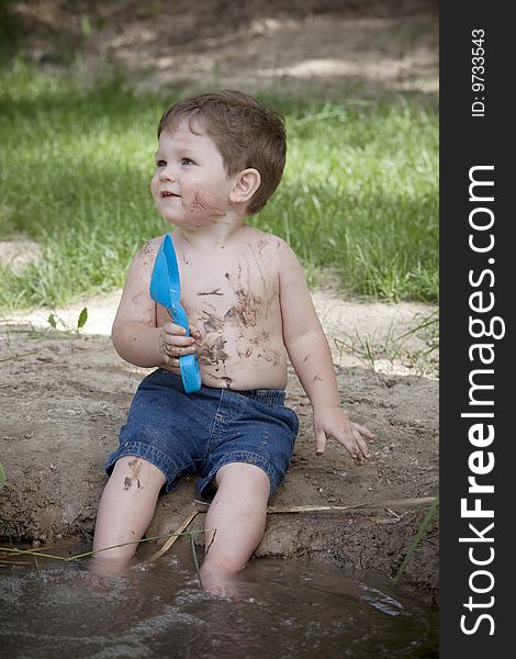 Little boy with muddy face and blue shovel