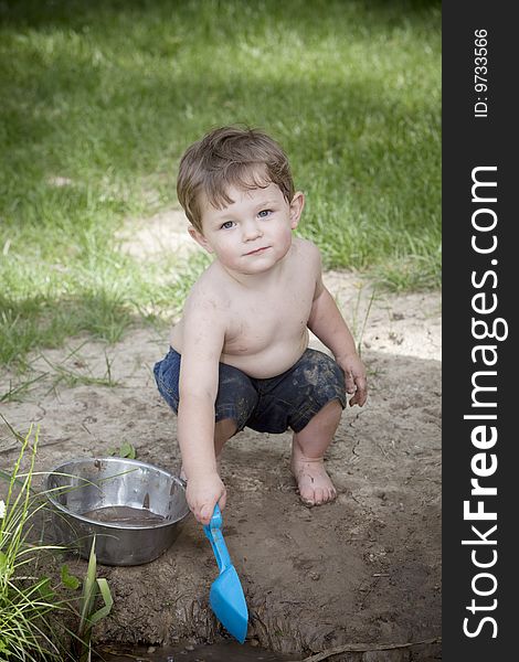 Little boy with muddy face and blue shovel