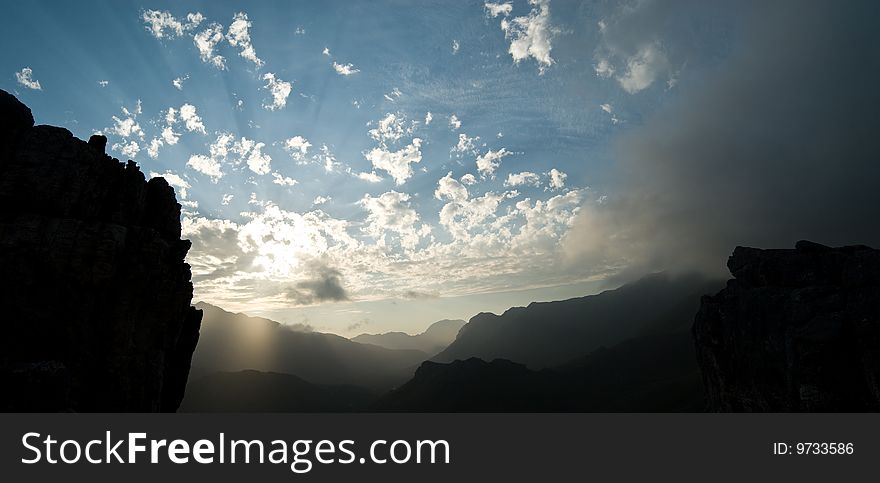 Sun rays breaking through clouds with mountains in foreground. Sun rays breaking through clouds with mountains in foreground