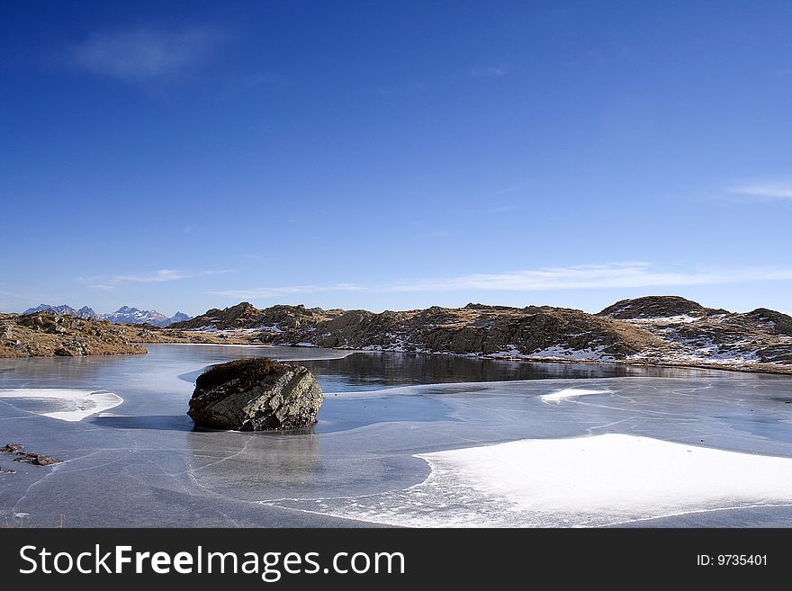 Frosted alpine lake in autumn with skyline mountains background, Valle Brembana, Italy.
