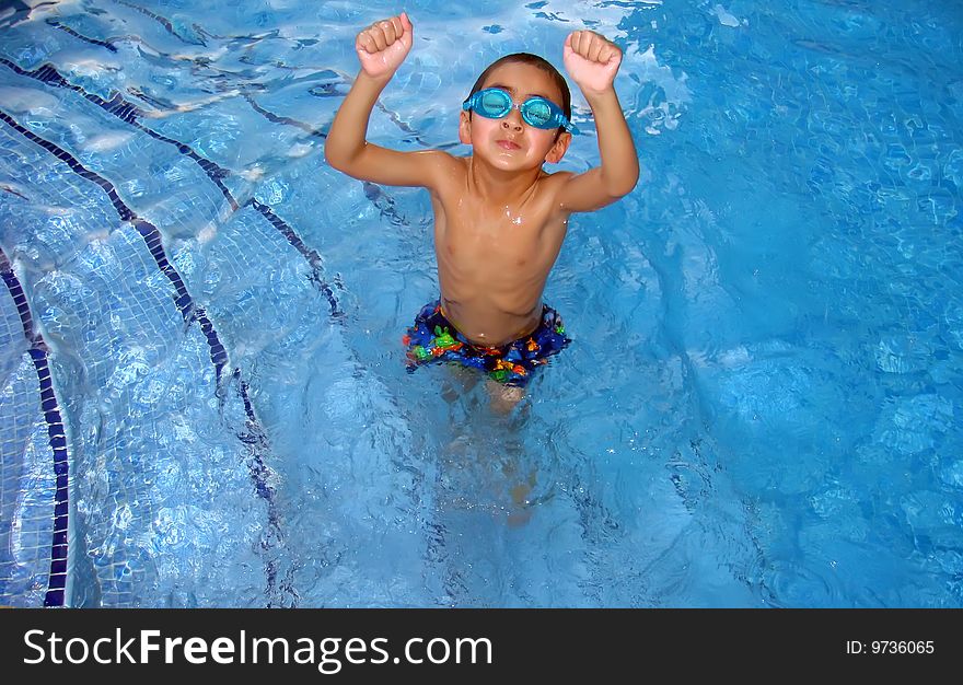 A young boy in the pool making the gesture of a champion by clenching his fists. A young boy in the pool making the gesture of a champion by clenching his fists.