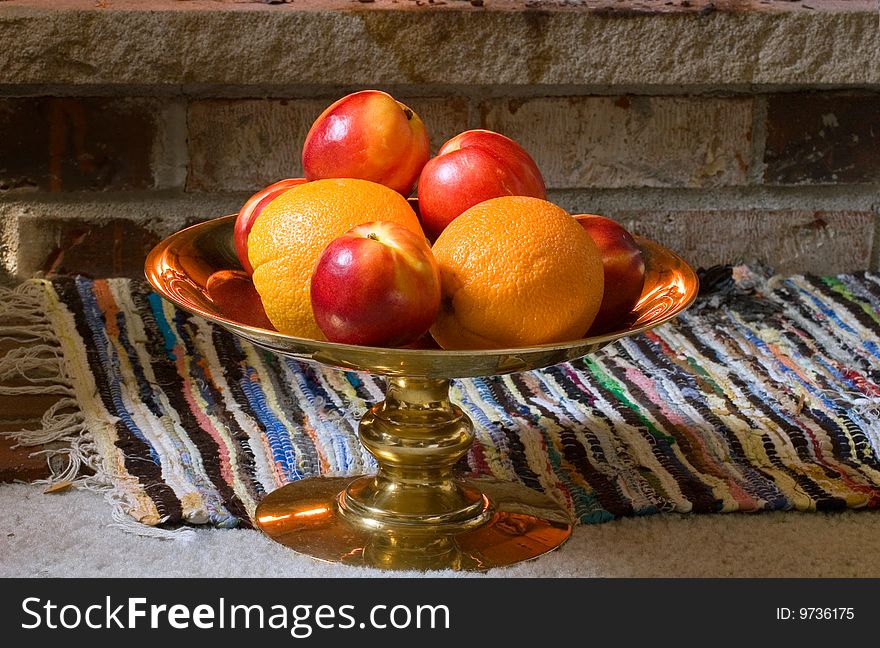 A copper vase with oranges and nectarines, standing on the floor. A copper vase with oranges and nectarines, standing on the floor