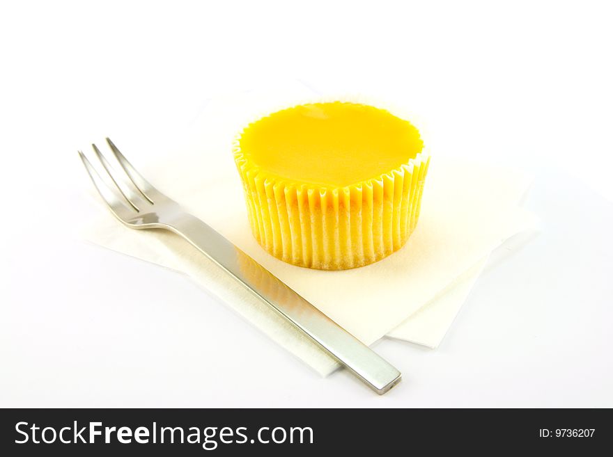 Delicious looking cup cake resting on two white napkins with a fork on a plain background