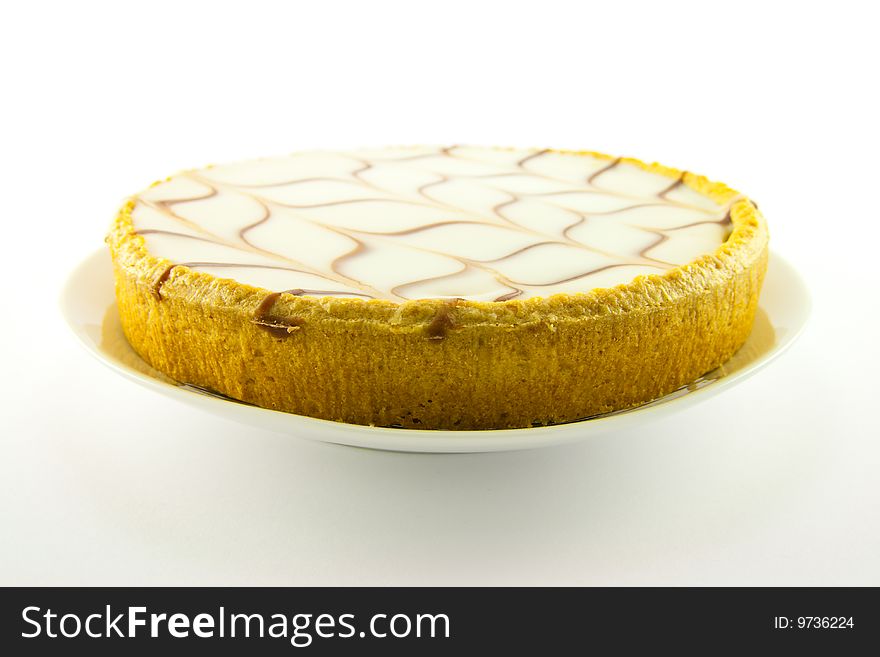 Delicious looking iced bakewell tart on a white plate with a plain background