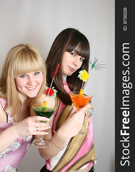 Two attractive young woman holding glass of cocktail in hand, smiling. Two attractive young woman holding glass of cocktail in hand, smiling.