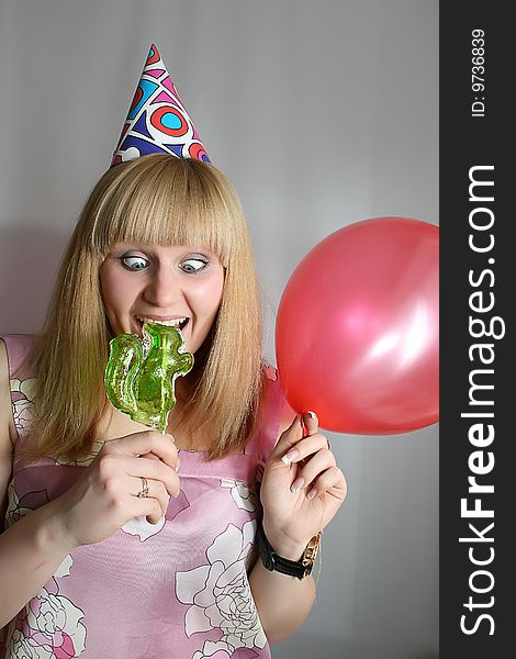 Young pretty woman in birthday cap with lollipop. Young pretty woman in birthday cap with lollipop