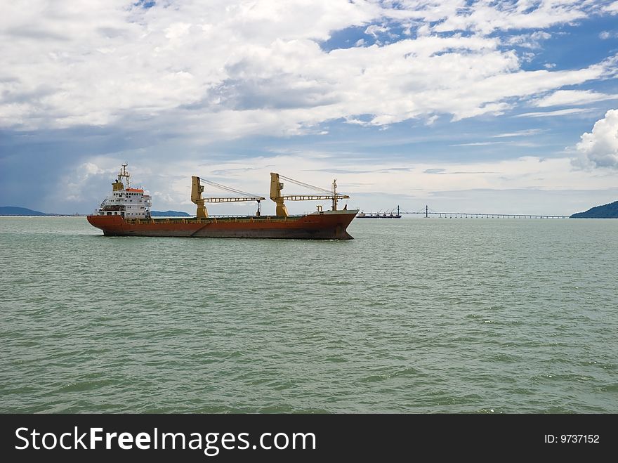 A large red cargo shipping vessel going through a strait. ADOBE RGB (1998) color profile.