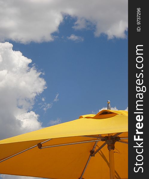 A large yellow umbrella under a sunny sky. A large yellow umbrella under a sunny sky.