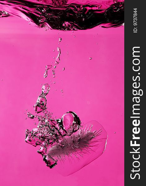 Ice with bubbles splashing underwater against pink background. Ice with bubbles splashing underwater against pink background