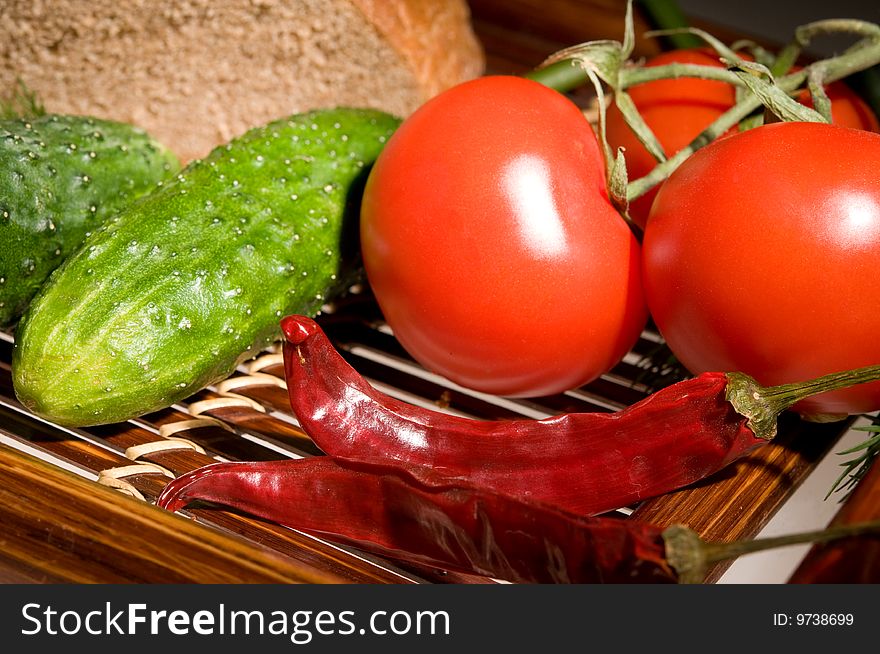 Three tomatoes, two cucumber and peppers with bread on wooden tray. Three tomatoes, two cucumber and peppers with bread on wooden tray
