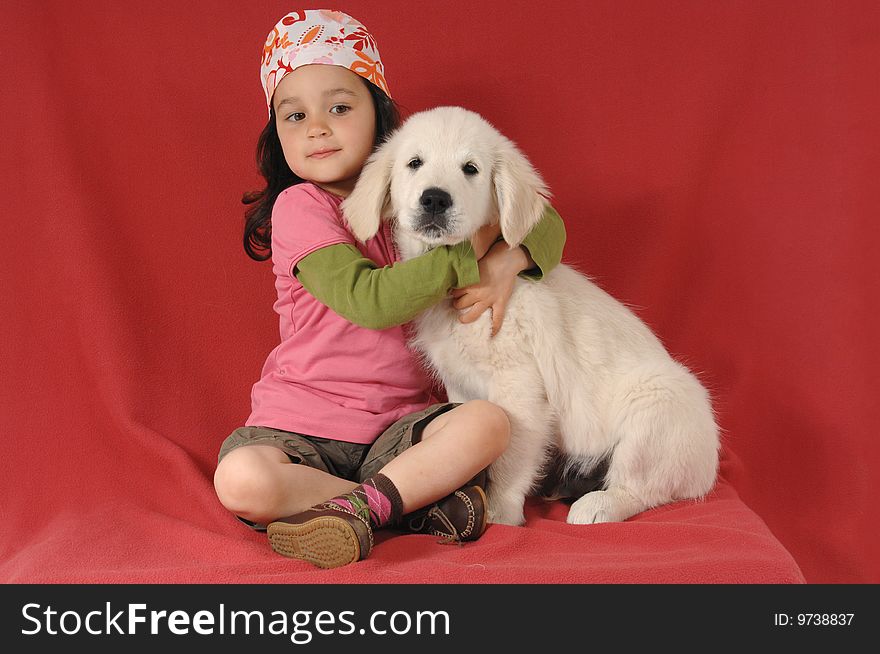 Little girl with a Golden retriever puppy on studio