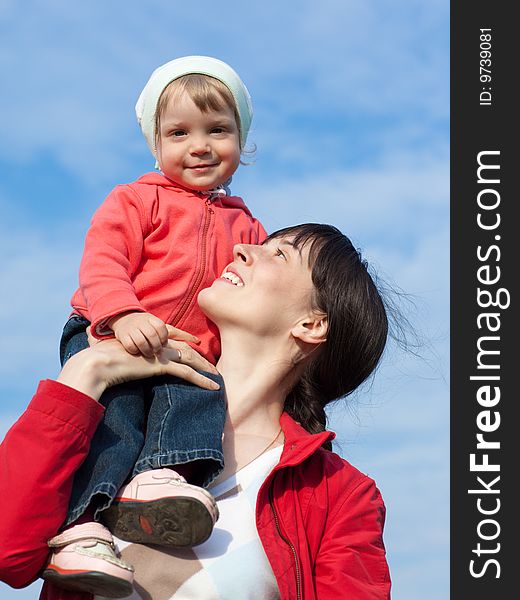 Portrait of a baby with mom outdoors on blue sky background