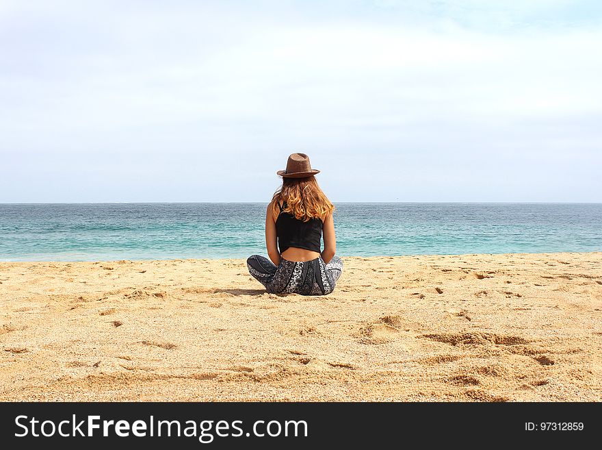 Woman Sitting on Seashore at Daytime
