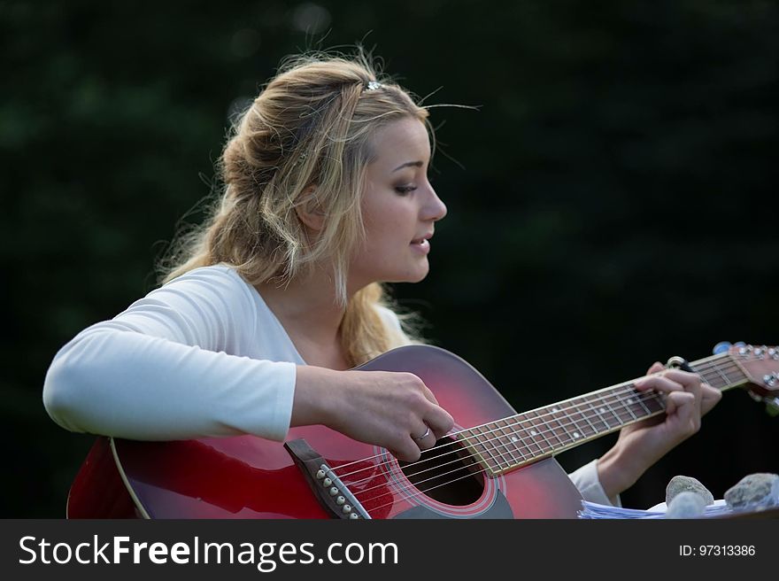 Woman&#x27;s Playing Red and Black Wooden Acoustic Guitar