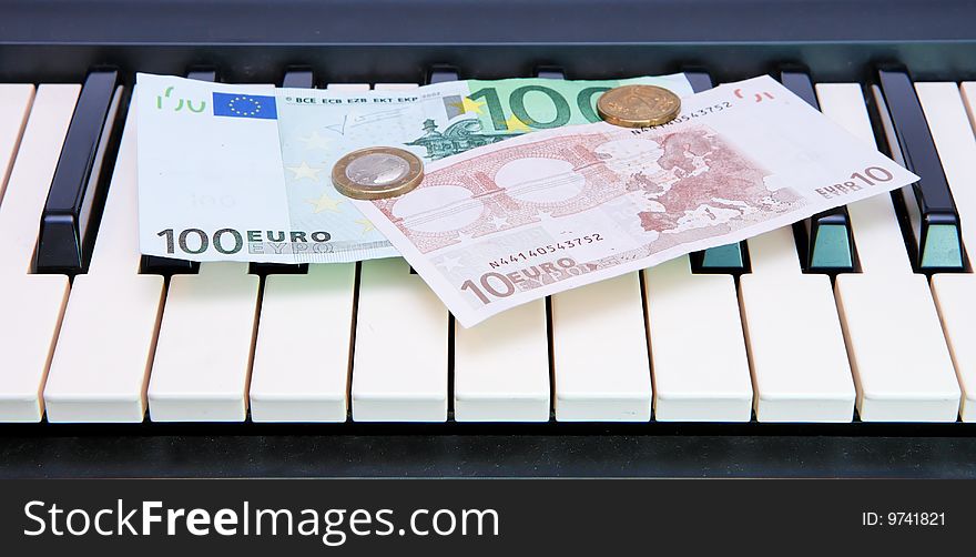 Euro bills and coins on electric organ keyboard. Euro bills and coins on electric organ keyboard