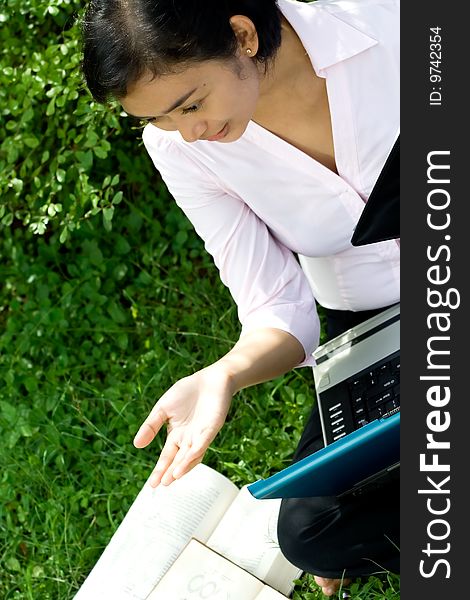 Pretty asian businesswoman seems to enjoy a discussion with her colleague during her happy working hours in green environment. Pretty asian businesswoman seems to enjoy a discussion with her colleague during her happy working hours in green environment