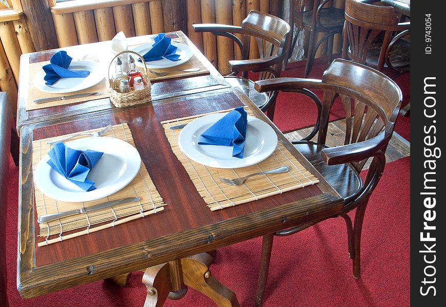 Plaits and silverware with blue napkin on table. Plaits and silverware with blue napkin on table