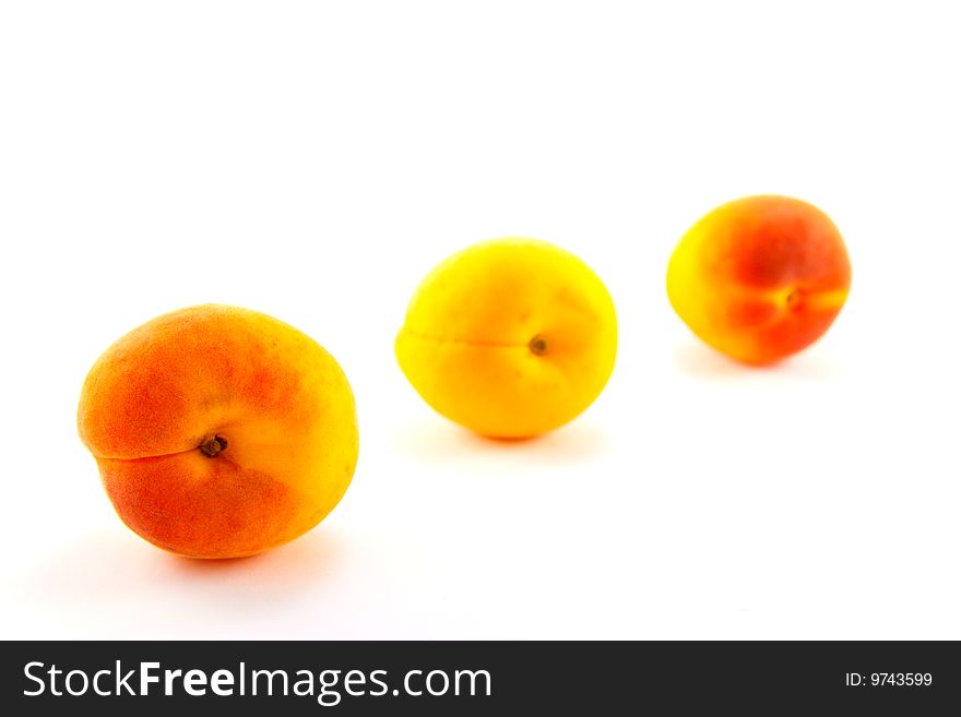 Three apricots in a line on a white background