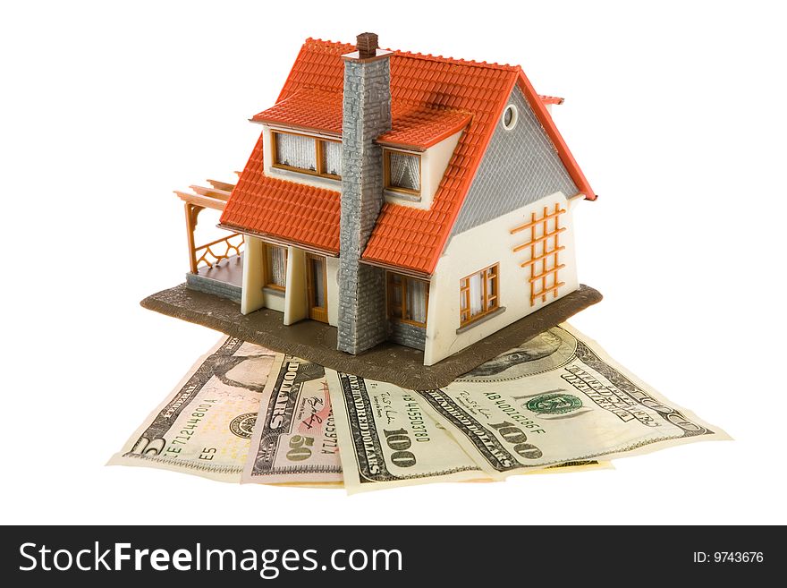 Miniature house with dollars isolated on white background