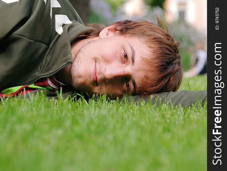 Young man lying on green grass