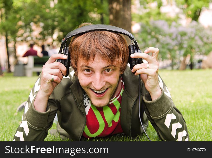 Young man young man wifh headphones sitting on the grass