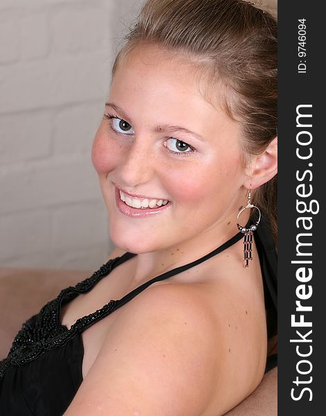 Relaxed young female sitting on a sofa with a friendly expression