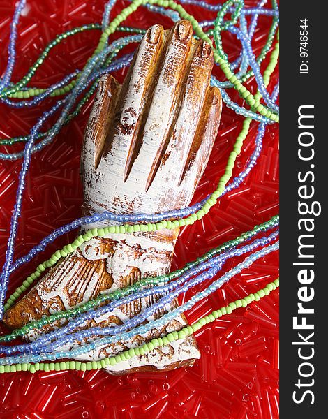 Ornate wooden hand on a bed of beads with strings. Ornate wooden hand on a bed of beads with strings