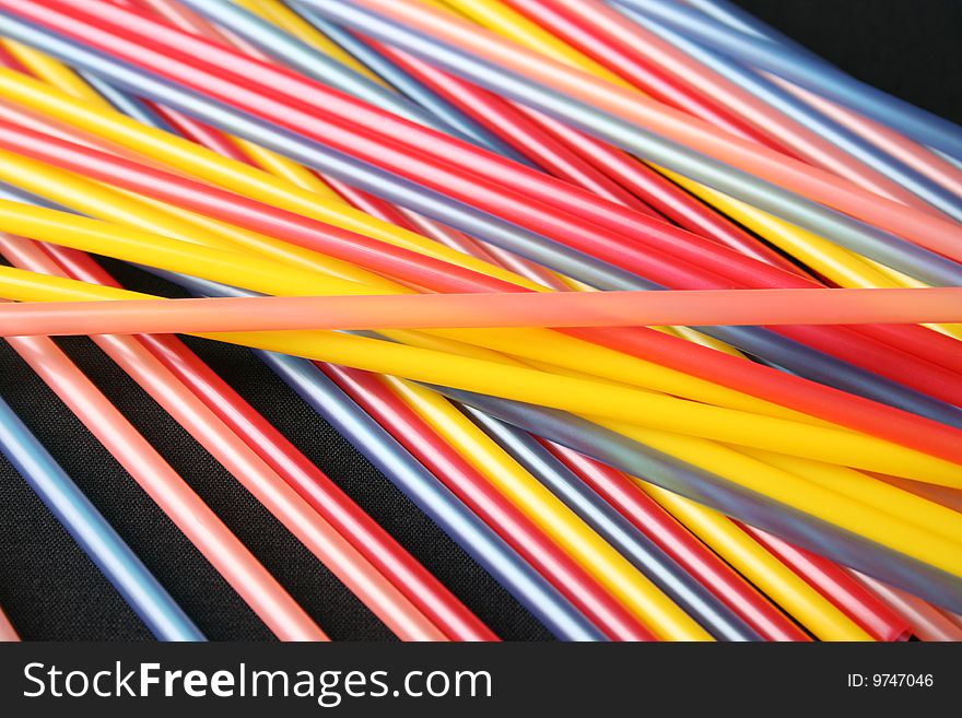 Straws on a black background in a variety of colours