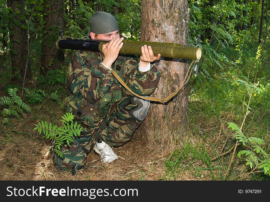 Young man in a camouflage shoots from a grenade launcher