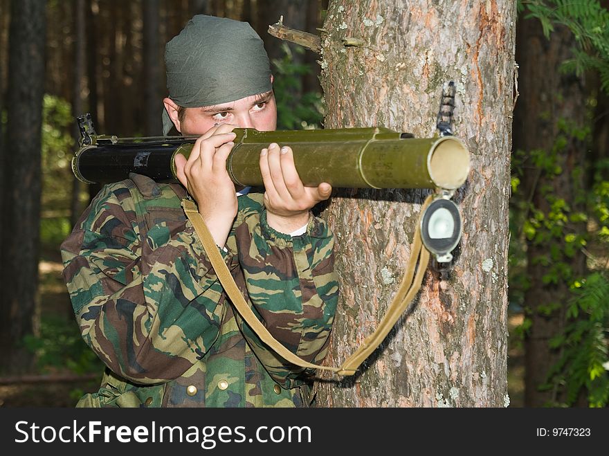 Young man in a camouflage shoots from a grenade launcher