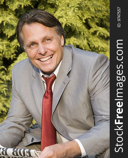 A colour portrait of a happy smiling businessman in his forties looking up and holding a newspaper in his hands. A colour portrait of a happy smiling businessman in his forties looking up and holding a newspaper in his hands.