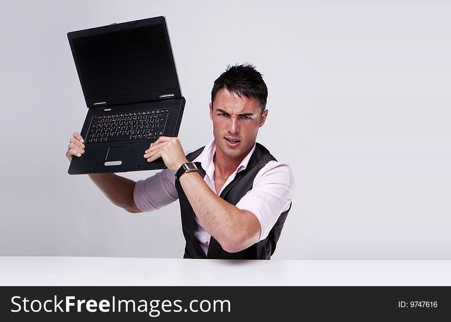 Brunette businessman holding a laptop trying to destroy it , problems at work