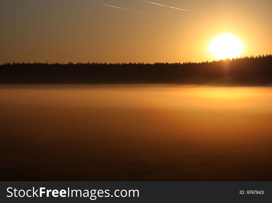 Sunrise over a foggy lake.