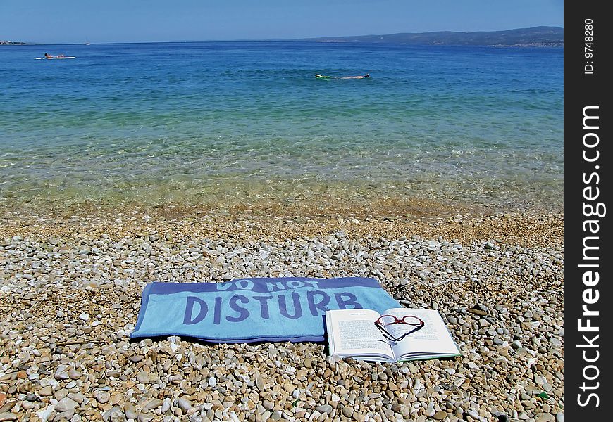 Towel do not disturb on beach with blue-green sea. Towel do not disturb on beach with blue-green sea