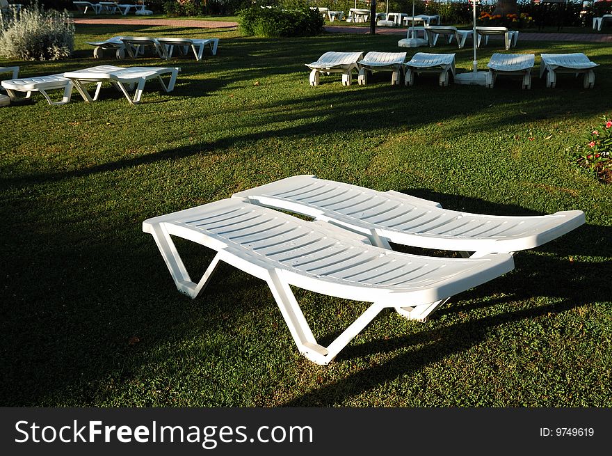 White sunbeds on a green grass