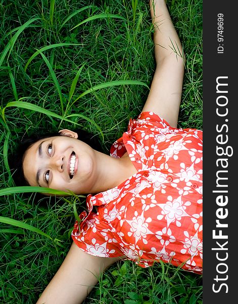 Happy asian woman laying on green grass seems to enjoy a beautiful day in nature. Happy asian woman laying on green grass seems to enjoy a beautiful day in nature.