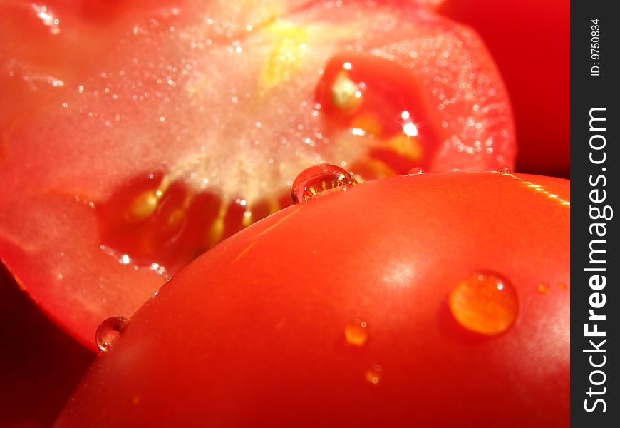 Halves of tomatoes with water drops one of which serve as spherical lens. Halves of tomatoes with water drops one of which serve as spherical lens