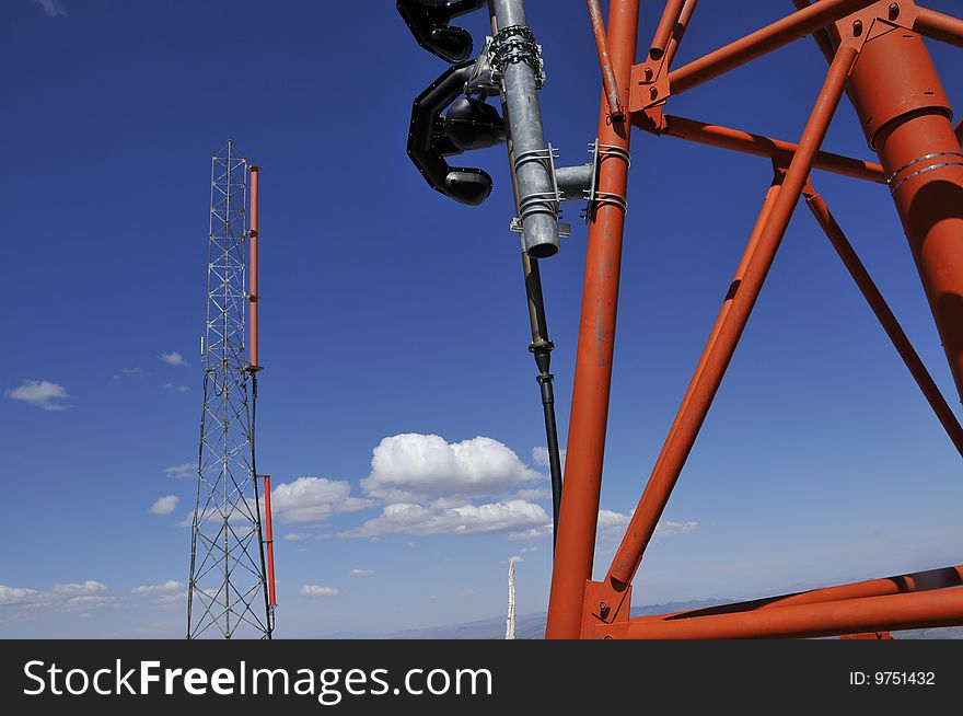 Wireless Weather and Aircraft Telecommunication Antennas on Top of Lattice Tower with Clouds and Tower in Background. Wireless Weather and Aircraft Telecommunication Antennas on Top of Lattice Tower with Clouds and Tower in Background