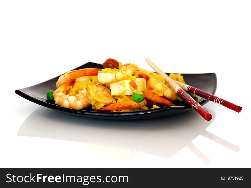 Chopsticks and paella on a black plate.