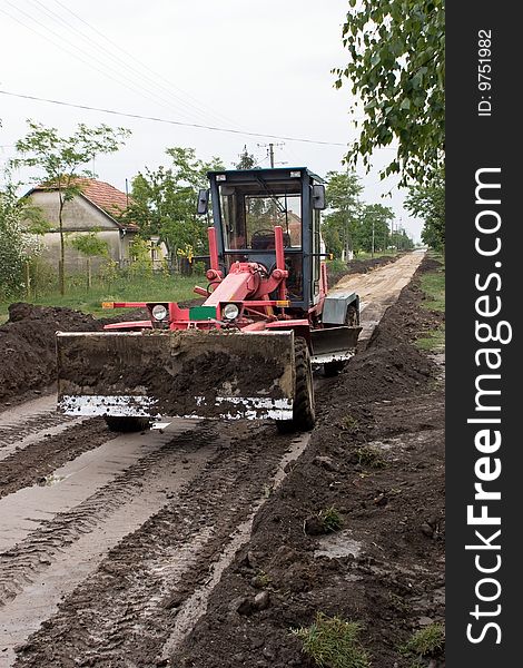 Grader equates ground for a new street in a village. Grader equates ground for a new street in a village