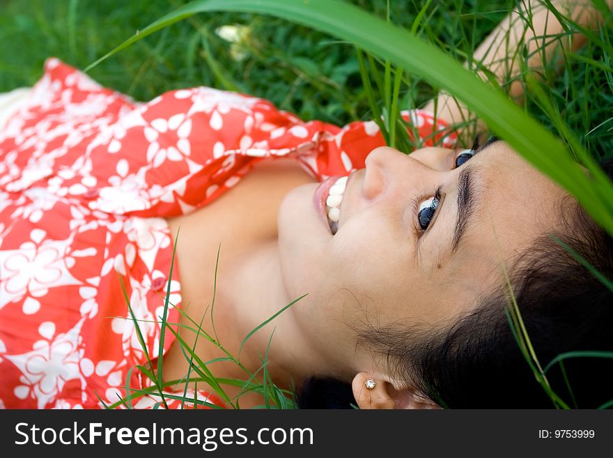 Closeup portrait of happy asian woman laying on green grass seems to enjoy a beautiful day in nature. Closeup portrait of happy asian woman laying on green grass seems to enjoy a beautiful day in nature.