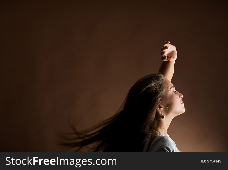 Fashion portrait of a young woman with hair lightly fluttering in the wind on a dark background. Fashion portrait of a young woman with hair lightly fluttering in the wind on a dark background