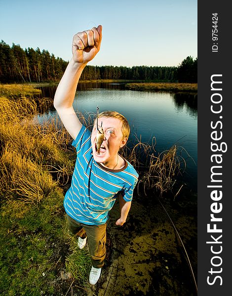 A cute guy showing off a crucian he has just caught. A cute guy showing off a crucian he has just caught