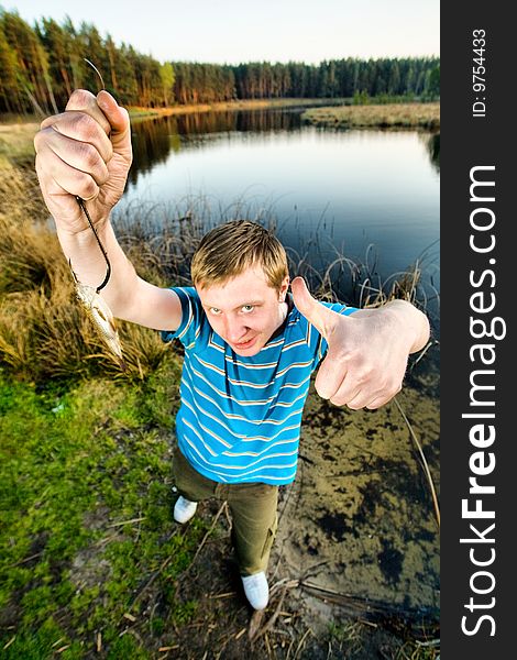 A cute guy showing off a crucian he has just caught. A cute guy showing off a crucian he has just caught