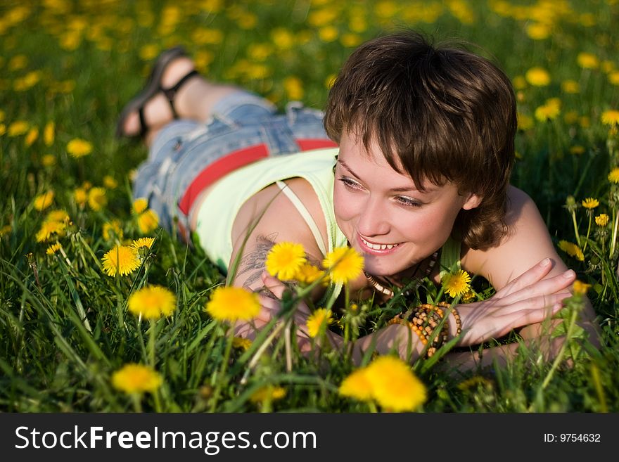 A young cheerful woman having fun on a dandelions glade