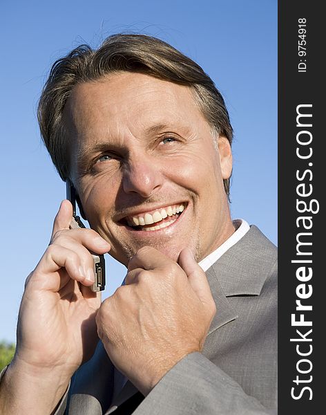 A colour portrait of a happy smiling businessman enjoying friendly chat on his cellphone. A colour portrait of a happy smiling businessman enjoying friendly chat on his cellphone.