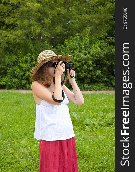 Portrait of a young girl in hat and sunglasses looking in digital camera. Portrait of a young girl in hat and sunglasses looking in digital camera