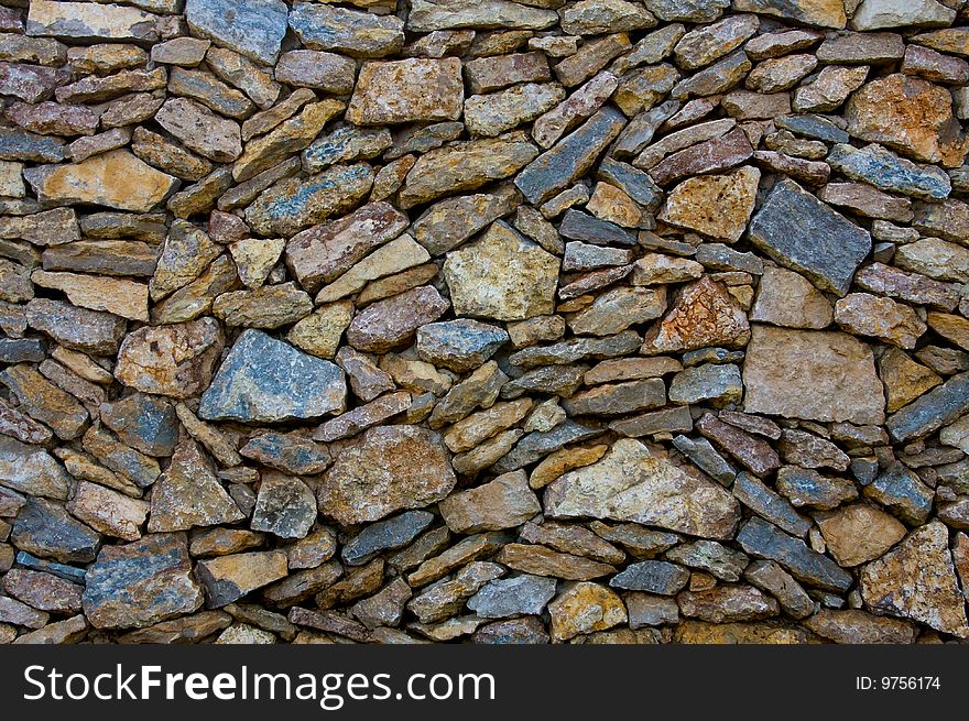A mix of natural stone is loose stacked to form a wall. A mix of natural stone is loose stacked to form a wall